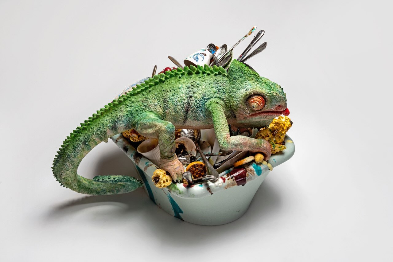 Un caméléon vert au-dessus d’un bassin d’objets, entièrement réalisé en céramique